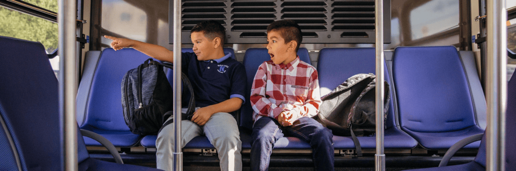 Boys on a bus looking excited as they look out the window
