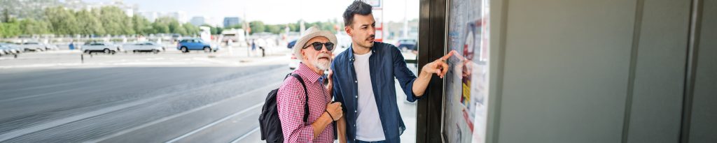 Two people looking at schedule board at a bus stop