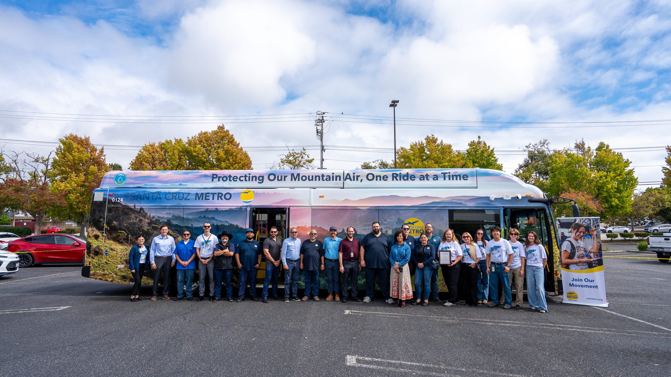 SC Metro employees standing in front of One Ride at a Time bus in parking lot.