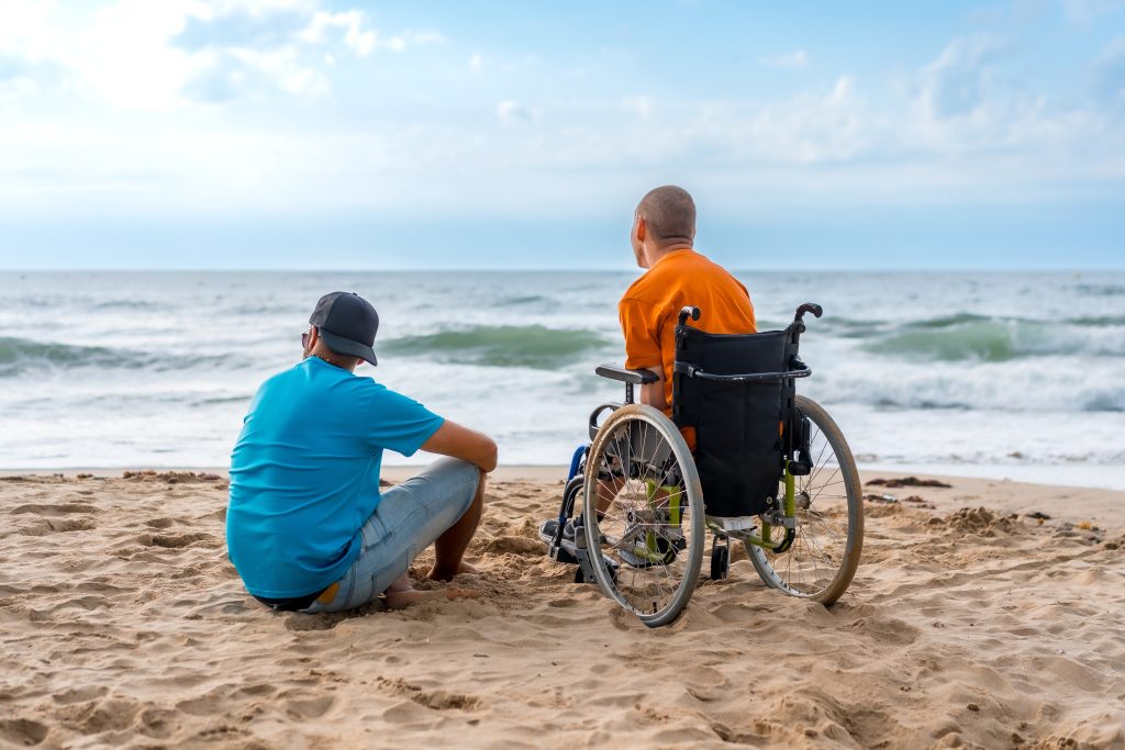 People sitting on the beach. One in a wheelchair